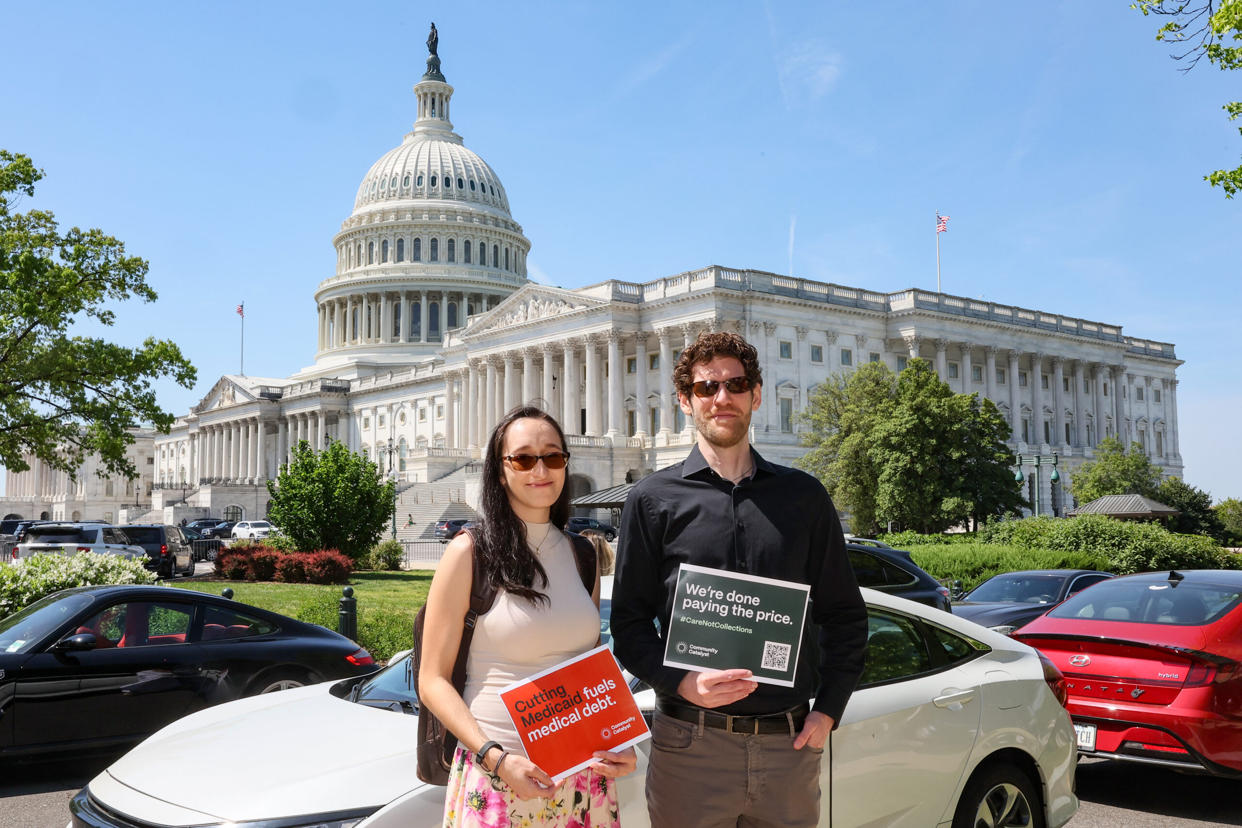 Two people pose in front of the Capitol with signs that read "Cutting Medicaid fuels medical debt" and "We're done paying the price."